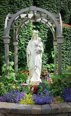 a statue in the middle of a flower garden