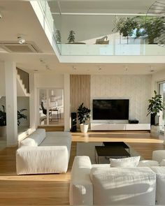 a living room filled with white furniture and a flat screen tv mounted to the wall