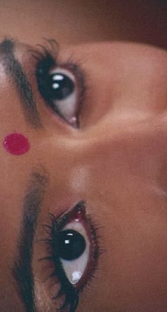 a close up of a woman's face with red circles on her eyes