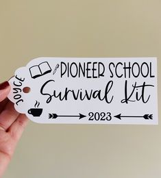 a person holding up a sticker that says pioneers school survival kit on it's side