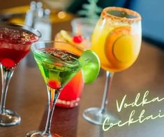 three different colored cocktails sitting on top of a table