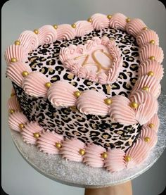 a leopard print cake with pink frosting and gold decorations on it's edges