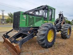 a large green tractor parked on top of a dry grass field