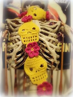 two crocheted skeletons sitting next to each other in front of a skeleton with flowers on it