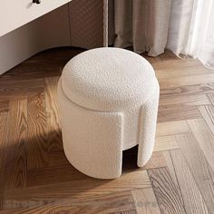 a white stool sitting on top of a hard wood floor next to a sink and mirror