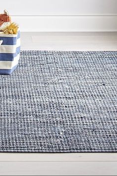 a blue and white rug with a basket full of seashells on top of it