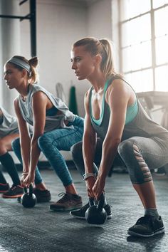 three women doing push ups with kettles in a gym