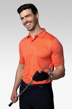 a man in an orange shirt is holding a golf club and smiling at the camera