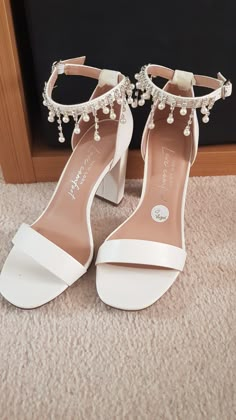 a pair of white high heeled shoes with pearls