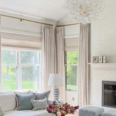 a living room filled with furniture and a fire place in front of a window covered in curtains