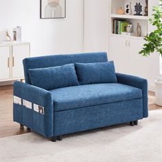 a blue couch sitting on top of a wooden floor next to a book shelf filled with books