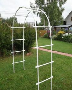 a white garden trellis sitting on top of a lush green field