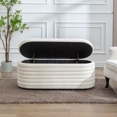 a white chair and ottoman with a black cushion on it in front of a wall