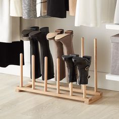 an organized closet with boots and clothes hanging on the rack, in front of a white wall