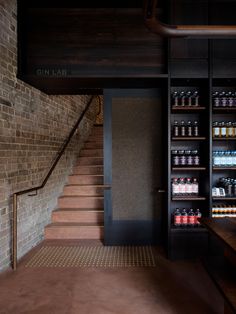 an empty room with stairs and shelves full of drinks on the wall next to it