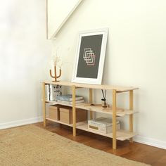 a shelf with some books on top of it next to a painting and a rug