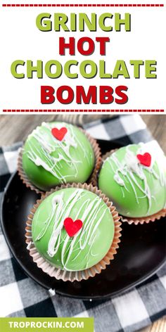 three green cupcakes with white icing and red hearts on them are sitting on a black plate