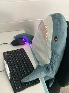 a stuffed shark sitting in front of a computer keyboard