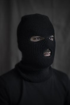 a man wearing a black mask and looking at the camera with an angry look on his face