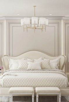 a large white bed sitting in a bedroom under a chandelier