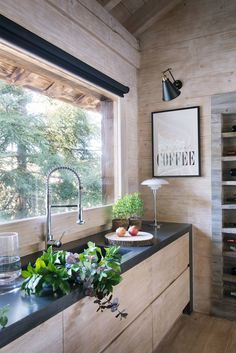 a kitchen with wooden walls and black counter tops next to a window filled with wine bottles