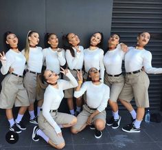 a group of women in white shirts and khaki pants posing for a photo