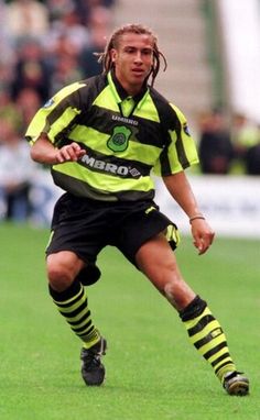 a soccer player is running with the ball in his hand and wearing black and yellow striped socks