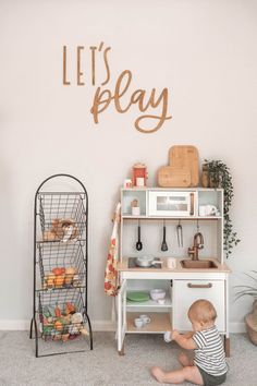 a toddler plays with his toys in the playroom at their home, which is decorated with let's play letters