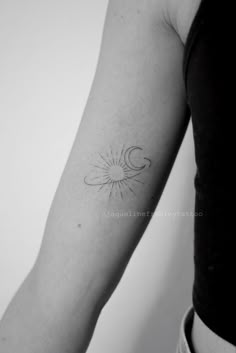 a woman's arm with a small sun and moon tattoo on it