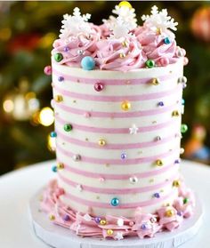 a pink and white striped cake with snowflakes on it's top sitting on a plate