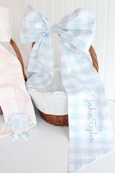 a basket with two baby bibs in it and a bow tie on the front