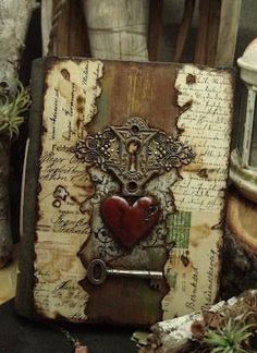 an old book with a red heart on it sitting next to some candles and other items