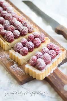 raspberry tarts on a cutting board with a knife