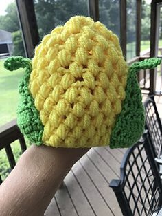 a hand holding up a crocheted turtle hat