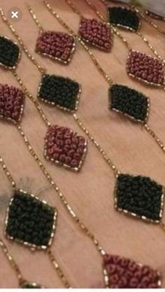 several rows of beads on a table with gold chains hanging from the top and bottom