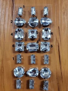 an assortment of diamond shapes and sizes on a wooden table with numbers in front of them