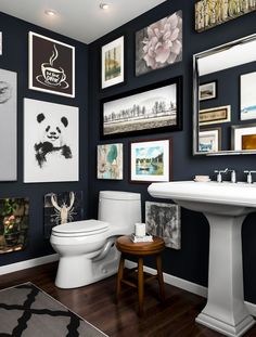 a white toilet sitting next to a sink in a bathroom under pictures on the wall