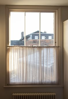 a window with sheer curtains in front of a brick wall and white radiator