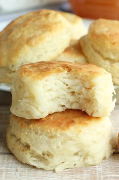 three biscuits stacked on top of each other next to a jar of jam and a spoon