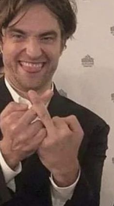 a man wearing a suit and tie making the v sign with his hands