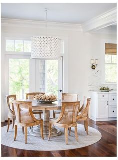 a dining room table and chairs in front of a window with white trim on the walls