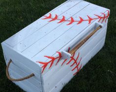 a baseball themed wooden box sitting on top of the grass with bats painted on it