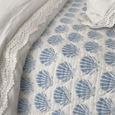 a white and blue bedspread with an embroidered shell design on the bedding