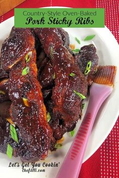 a white plate topped with ribs covered in bbq sauce next to a pink spatula