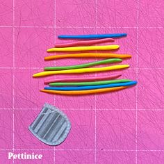 several different colored toothbrushes laying on a pink surface next to a piece of cloth