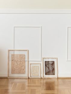 four framed pictures on the wall in an empty room with hard wood flooring and white walls