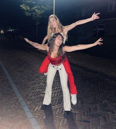 two women in red and white are posing for the camera with their arms spread out