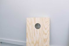 an unfinished piece of wood with a hole in the middle and white walls behind it