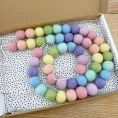 a box filled with different colored balls on top of a wooden floor next to a string