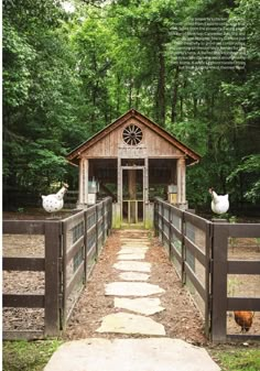 a small wooden building in the middle of a forest with two chickens on it's side